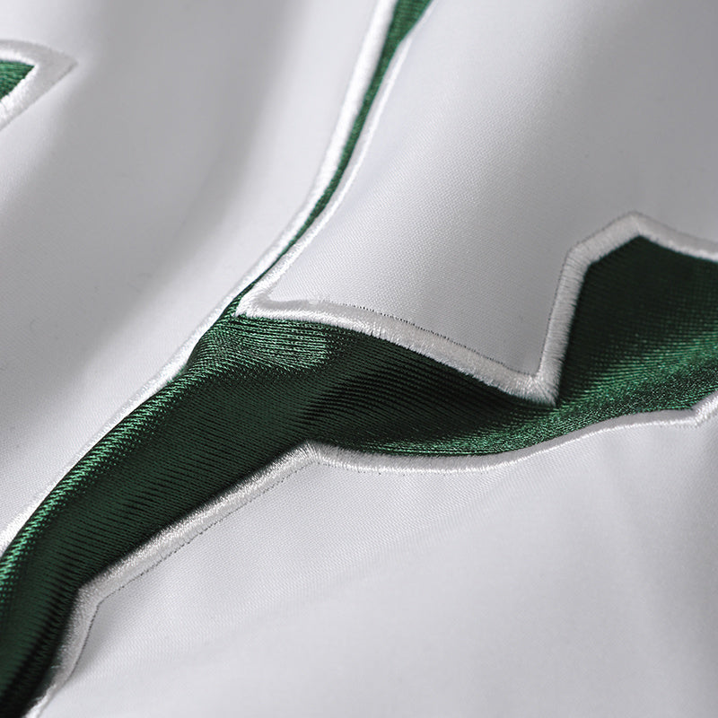 Close-up of a white football jersey with green satin trim and embroidered number detailing, varsity streetwear style