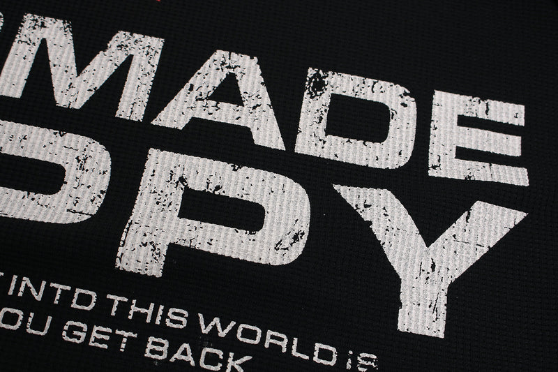 Close-up of white distressed MADE BY text on black waffle knit sweatshirt back