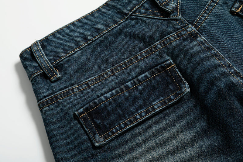 Close-up of back pocket and yoke stitching on dark wash jeans with a flap pocket