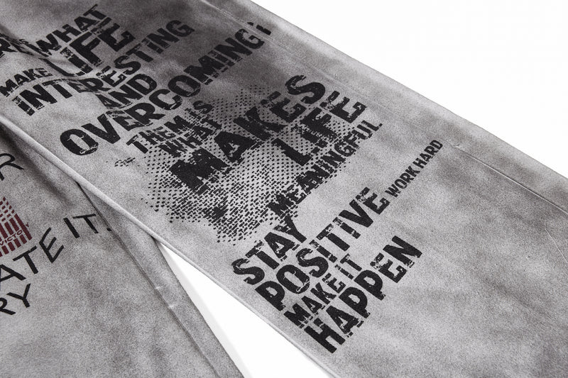 Close-up of larger black graphic text print on gray washed denim leg