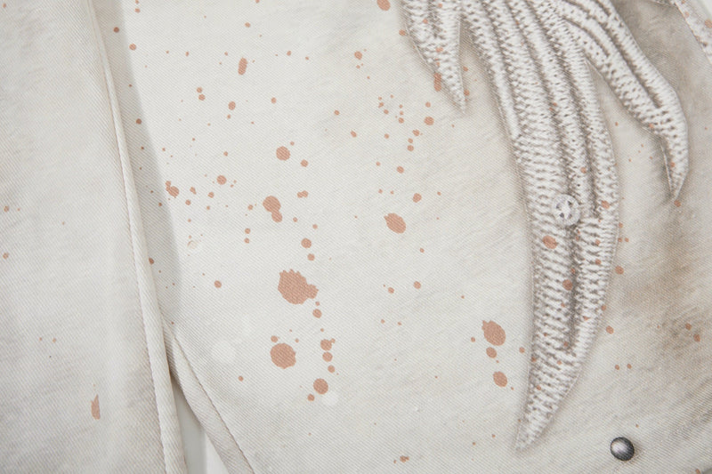 Close-up of cream denim with splatter print and wing graphic along the side
