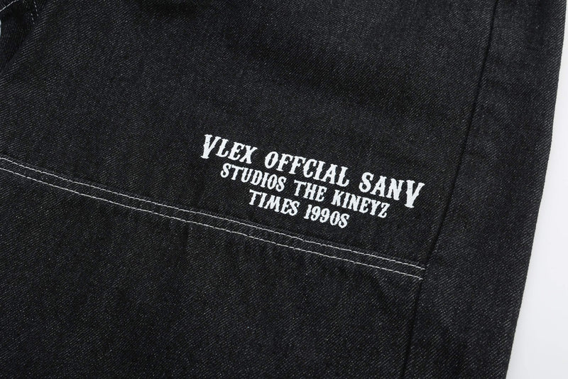 Back leg of black denim shorts with white printed text near the hem