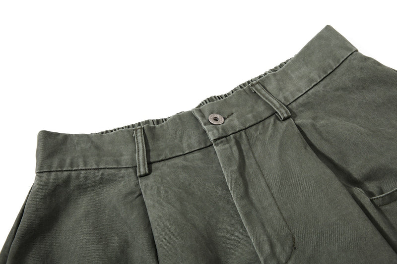 Close-up of olive green pant waist with button closure and belt loop