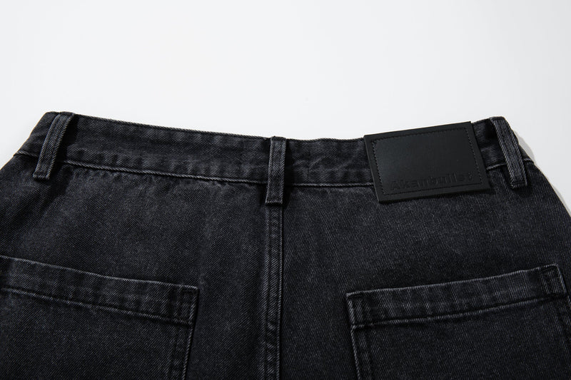 Back waistband detail of washed charcoal denim pants with belt loops and logo patch