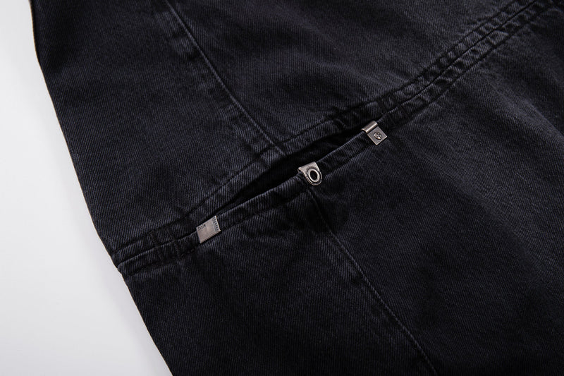 Close-up of side split seam on dark wash jeans with metal rivet details