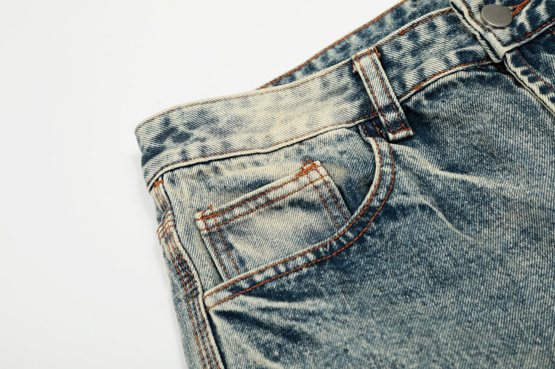 Close-up of light wash jeans front pocket and waistband with metal button and fading