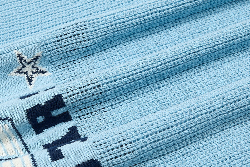Close-up of light blue knitted varsity polo fabric with dark navy collegiate lettering and textured weave