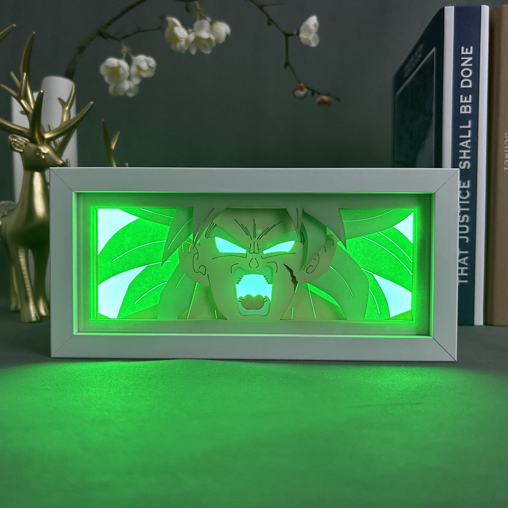 The Seakoff Dragon Ball Z Anime Light Box vividly displays Broly in 3D with dynamic, color-changing LED effects. This rectangular lamp is set against a backdrop of decorative elements, including a gold deer figurine and books on a shelf.