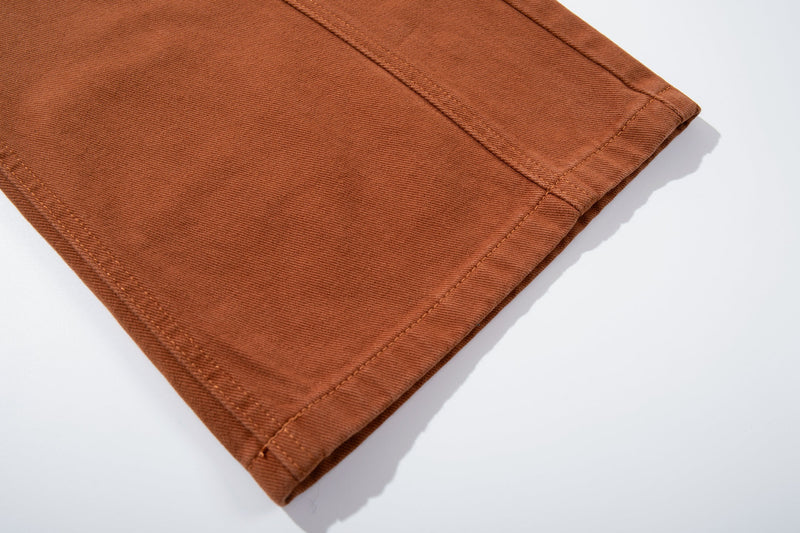 Close-up of the hem on rust brown jeans with double-stitched cuff