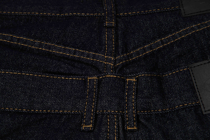 Close-up of rear waistband seam and belt loops on dark wash denim shorts