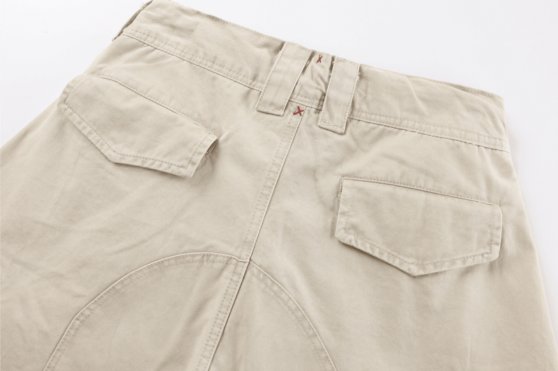 Close-up of beige cargo pants back waistband and pocket flaps with curved seam detail