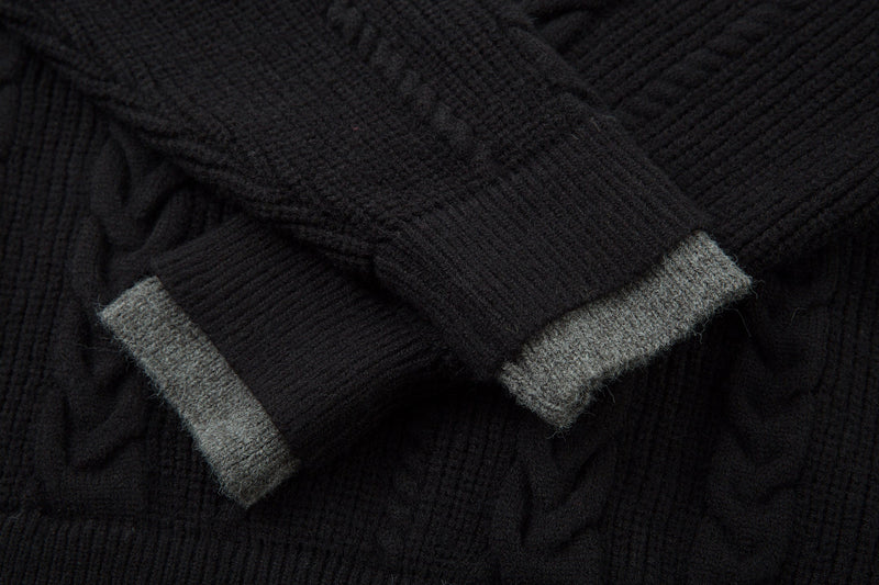 Close-up of black cuff with gray ribbed trim on cable knit sweater