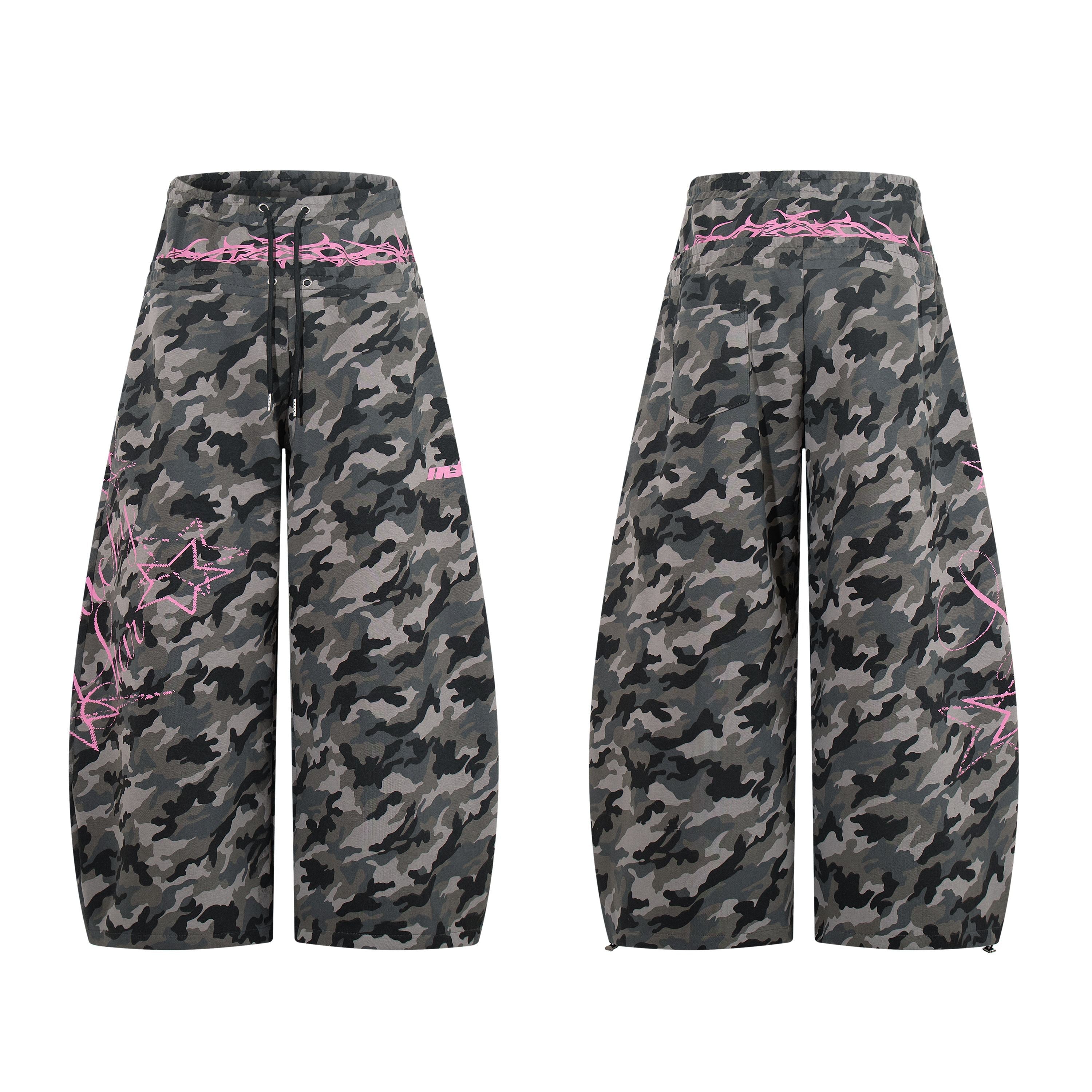 Grey camouflage wide-leg baggy pants with pink graffiti script, star embroidery, and barbed-wire waistband detail, front and