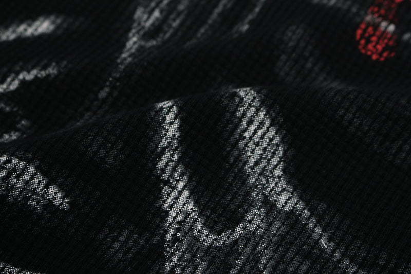 Close-up of a black graphic tee with distressed white ribcage print and a small red heart detail