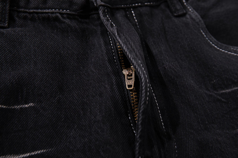 Close-up of the front zipper fly on dark wash denim with metal zipper hardware