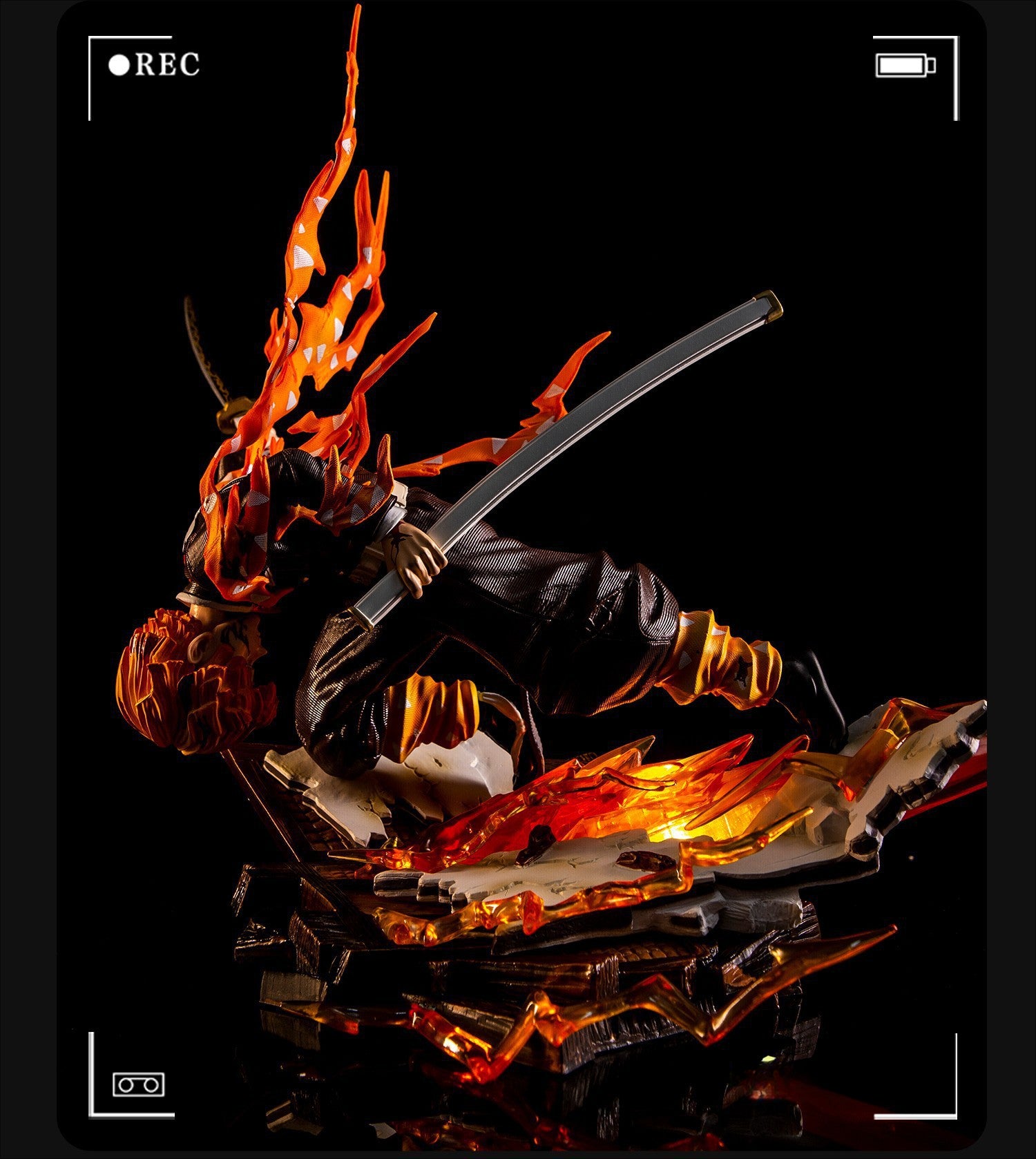 The Rengoku Kyojuro Demon Slayer Figure by Demon Slayer is a 28cm high-quality PVC model showcasing the Flame Hashira with fiery hair and sword, poised on a black base with fire elements, resembling a video frame with &quot;REC&quot; and camera icons.