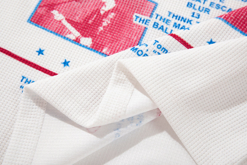 Close-up of white ringer T-shirt fabric with red and blue vintage band graphic print and folded sleeve detail
