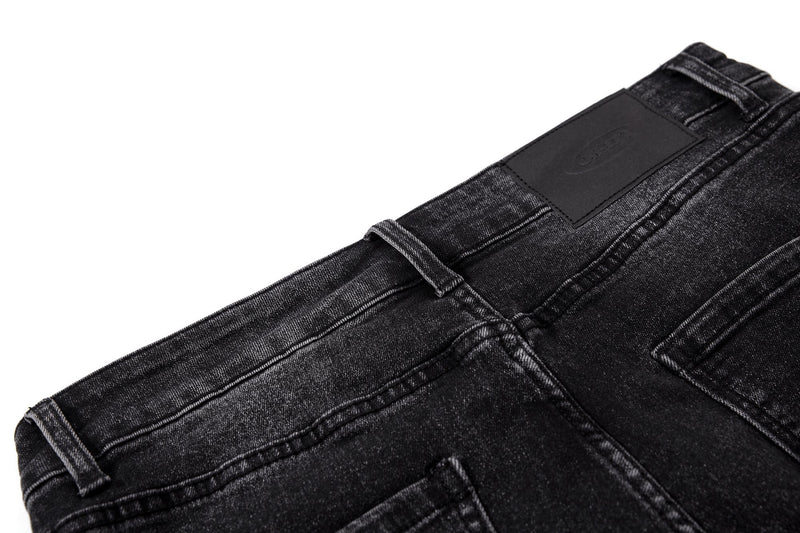 Close-up of black denim back waistband with leather patch and belt loops
