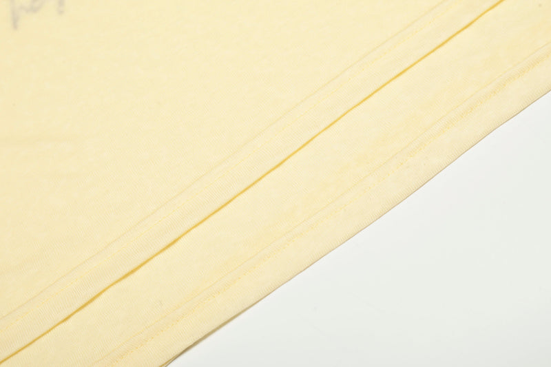 Close-up of light yellow sleeve seam and cuff hem on soft cotton fabric