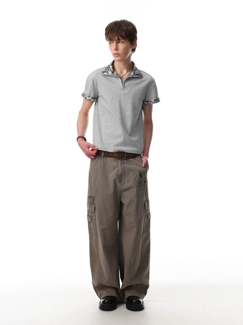 Gray quarter-zip polo shirt with leopard print collar and sleeve trim, styled on a model with cargo pants