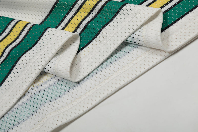 Close-up of a white mesh football jersey with green and yellow striped graphic detailing and folded fabric texture