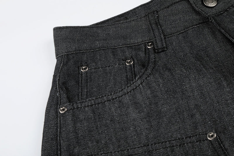 Close-up of left front pocket and waistband on black raw denim shorts