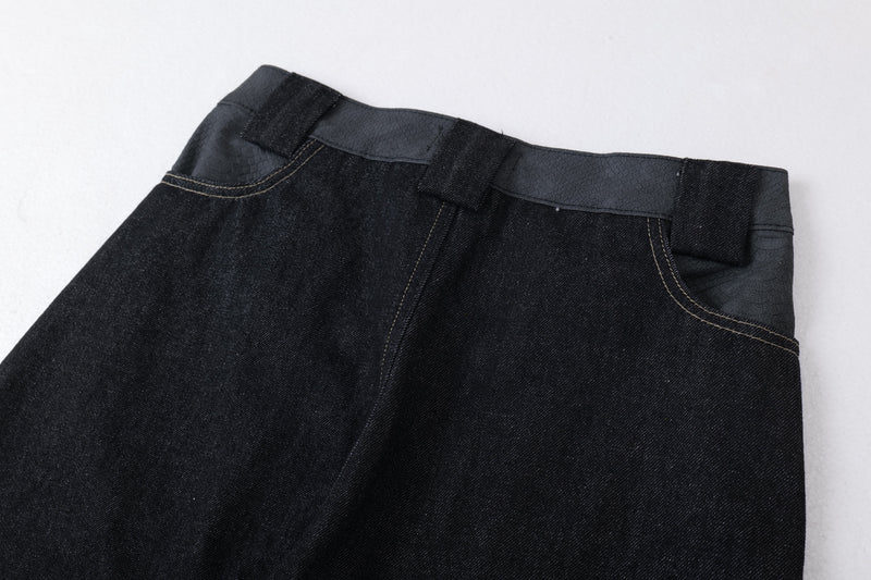 Close-up of the waistband on dark denim jeans with belt loops and topstitching