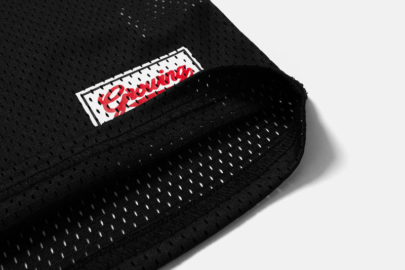Black mesh jersey hem close-up with woven label and perforated side opening