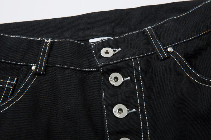 Close-up of black jeans front fly with silver buttons and white contrast stitching