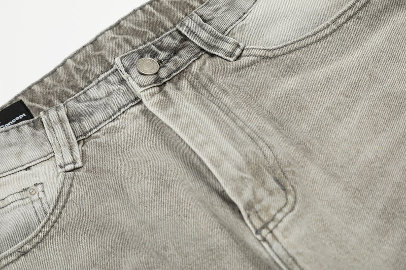 Close-up of front waistband and pocket stitching on light gray distressed jeans