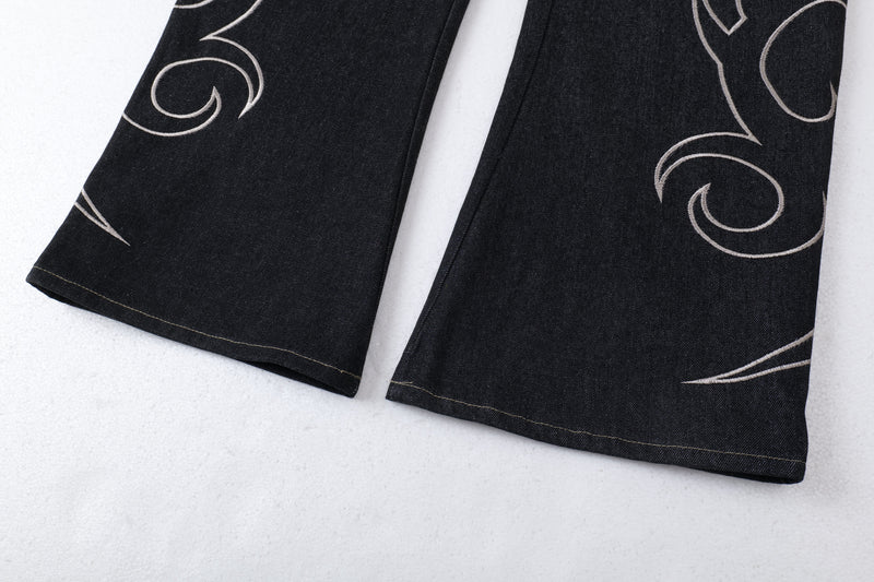 Close-up of the lower leg hems on dark denim balloon jeans with tribal embroidery