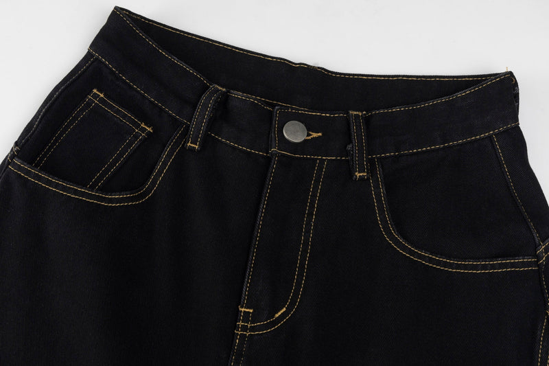 Close-up of the waistband on black denim jeans with belt loops, button, and tan stitching
