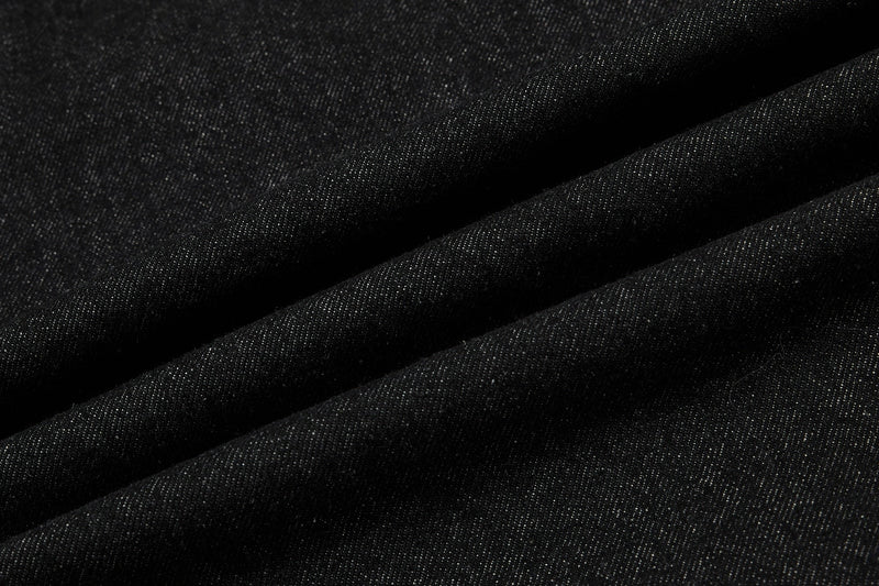 Close-up of black denim fabric folds with a textured weave
