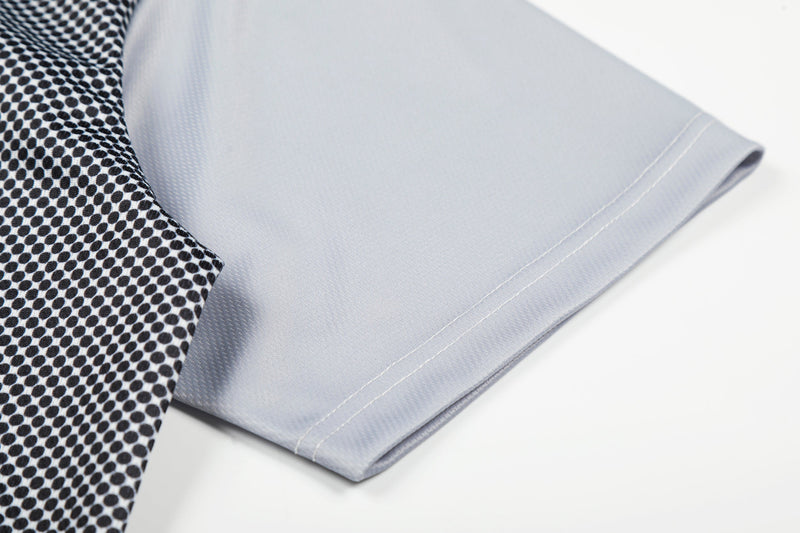 Close-up of a light gray mesh jersey hem with black polka dot trim and neat stitched edge