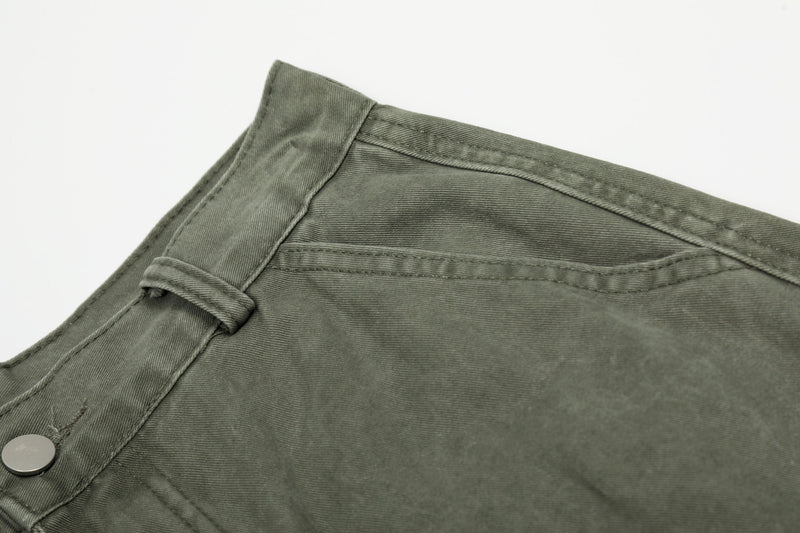 Close-up of olive green pants waistband, belt loop and side seam stitching