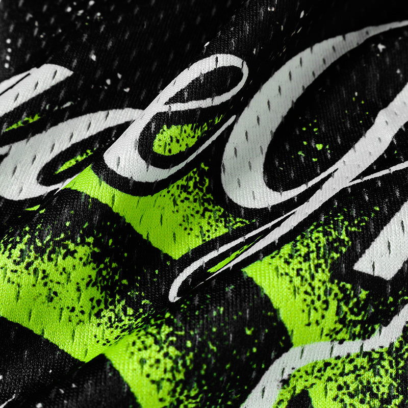 Close-up of black mesh football jersey with neon green splatter and bold white gothic lettering