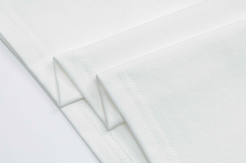 White folded graphic tee with visible hem stitching and smooth cotton fabric texture