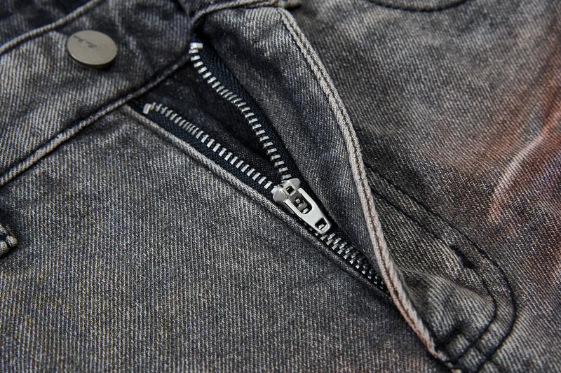 Close-up of the front zipper and button fly on gray distressed denim pants