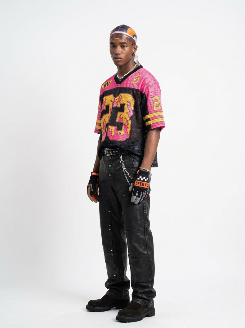 Model wearing a pink and black mesh jersey with flame graphic, number 23 detail, and streetwear football style