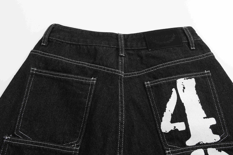 Rear waistband and pockets of black denim shorts with a large white letter print