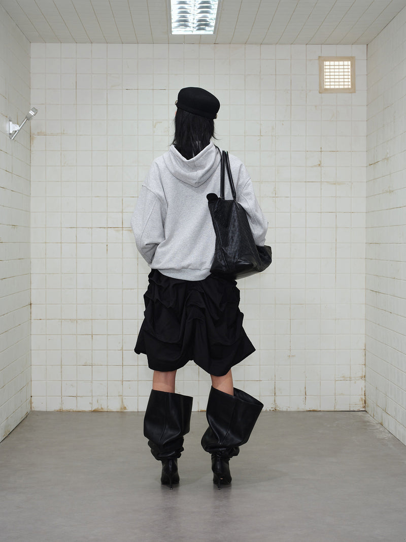 Back view of grey hooded sweatshirt with black skirt and black tote bag