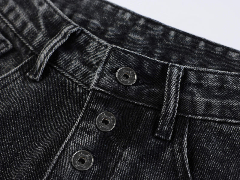 Close-up of black denim front button fly and waistband seam