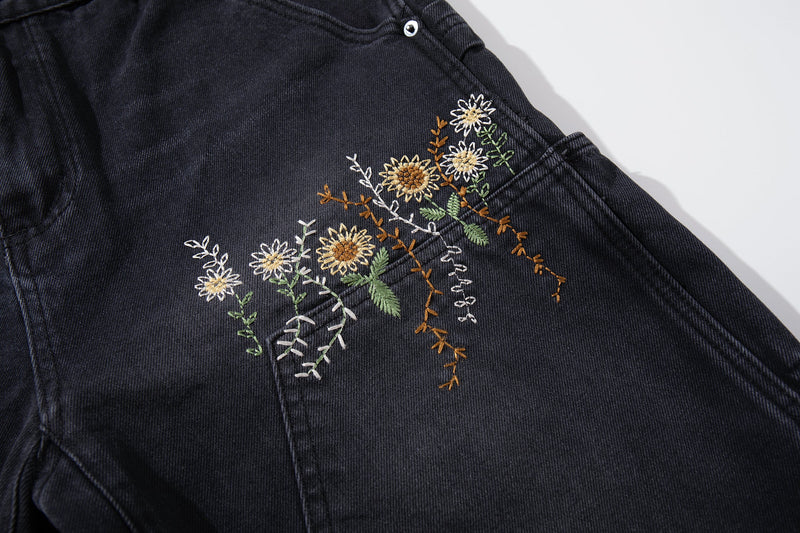 Close-up of floral embroidery on the front thigh of washed black jeans