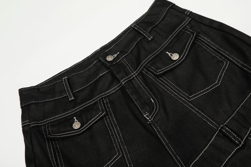 Close-up of the front waistband and pockets on black denim pants with white contrast stitching