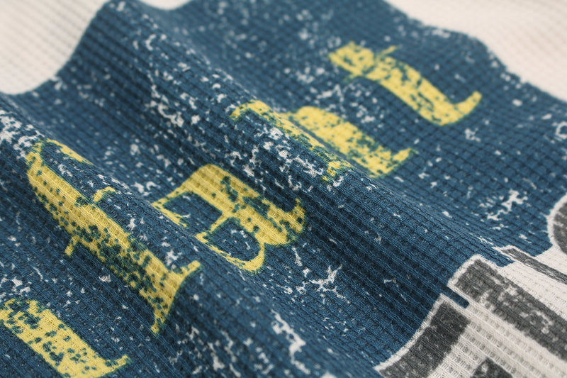 Close-up of blue printed block with yellow letters on waffle-knit fabric