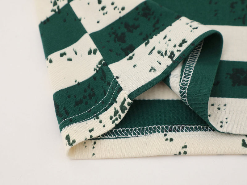 Close-up of green and cream striped tee hem with folded sleeve and stitching