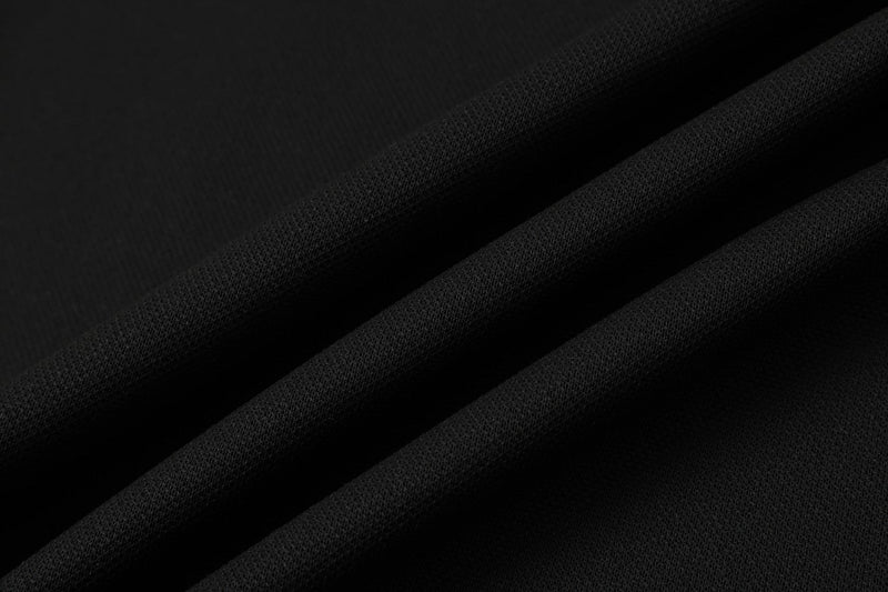 Close-up of black textured fabric with diagonal folds, showing the gothic polo shirt material detail