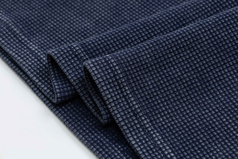 Close-up of folded navy blue textured polo tee fabric with a vintage washed waffle knit finish