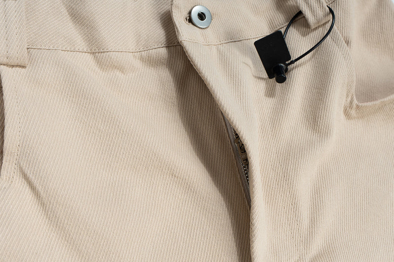 Close-up of beige cargo shorts front pocket, zipper, and drawcord detail