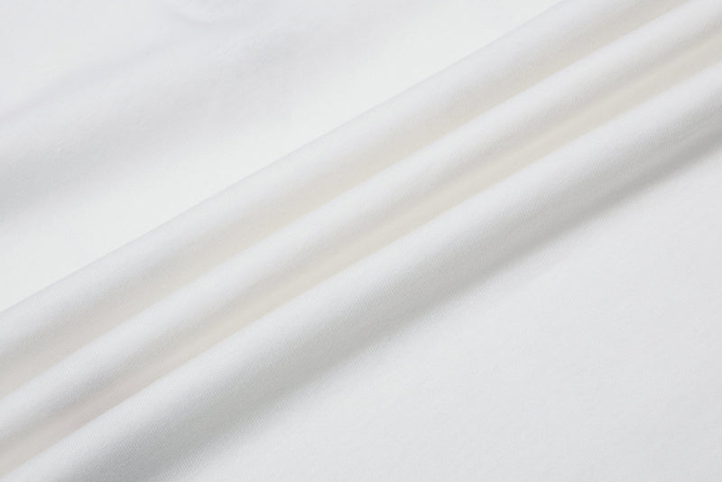 White fabric close-up with soft diagonal folds, showing a clean textured surface for a men’s polo shirt